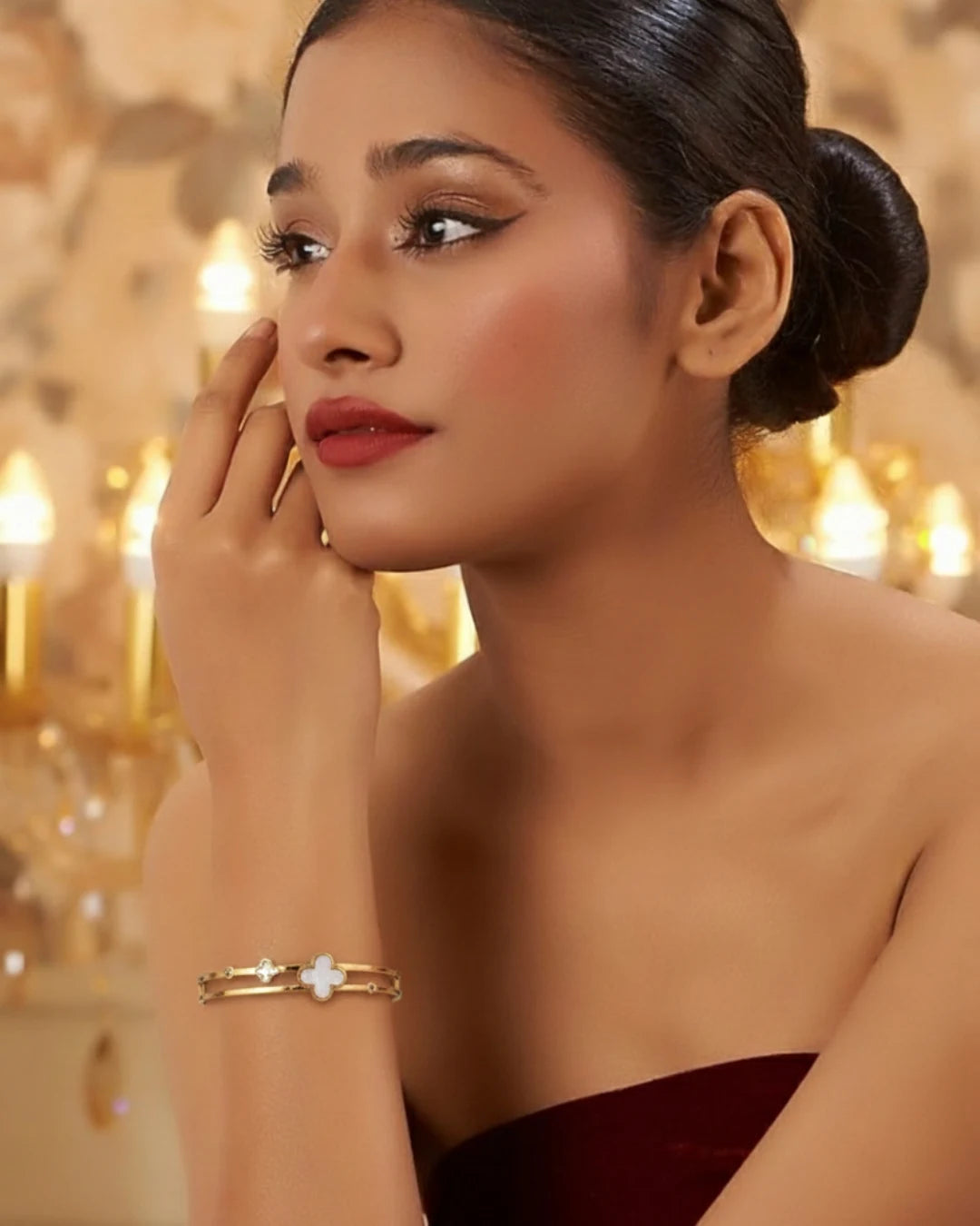 Woman wearing a gold bracelet with a blurred candlelit background